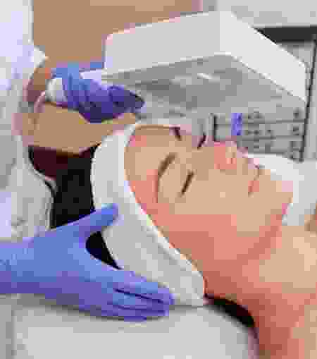 A woman getting her face cleaned by an esthetician.