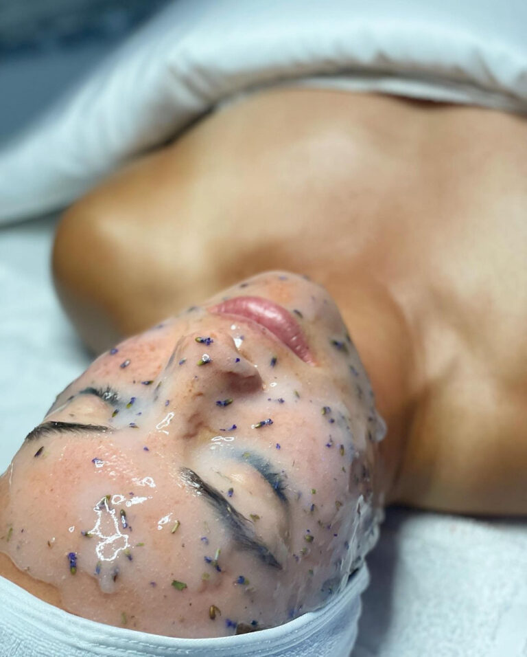 Person relaxing during a Face of Jules skincare treatment, lying down with a translucent, speckled facial mask in Los Angeles.