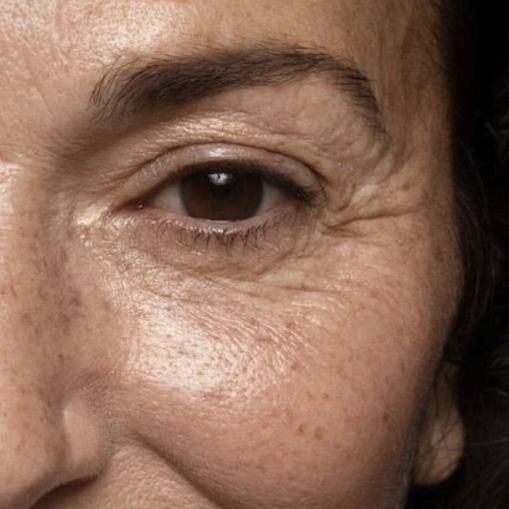 Close-up of the face of Jules in Los Angeles, showing wrinkles, fine lines, and a brown eye with arched eyebrow.